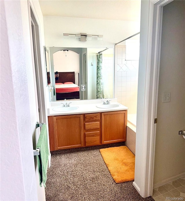 bathroom with double vanity, tiled shower / bath combo, a sink, and ensuite bathroom