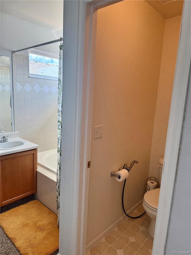 full bath with toilet, baseboards, tiled shower / bath, and vanity