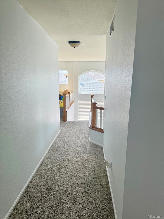 corridor with visible vents, baseboards, carpet flooring, and an upstairs landing