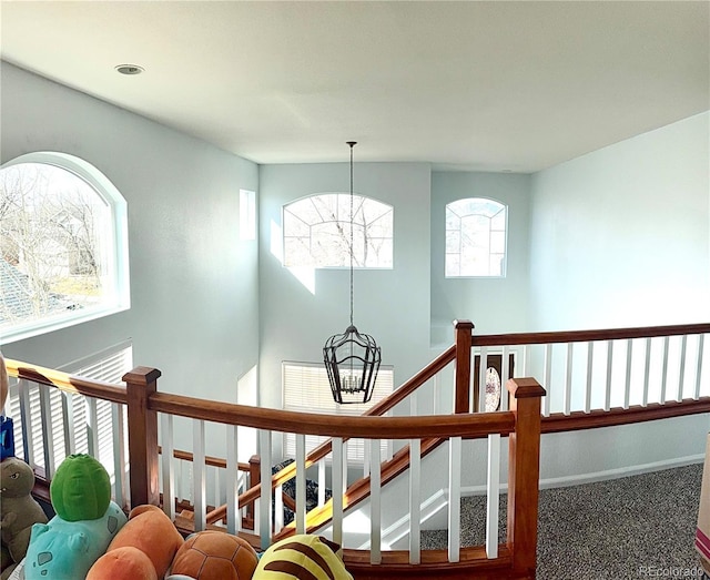 stairway with a chandelier, carpet floors, and baseboards