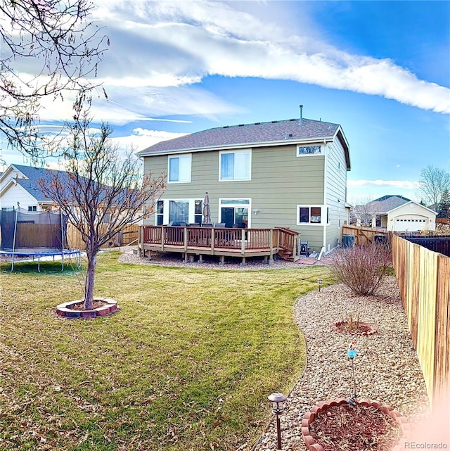 rear view of house with a yard, a fenced backyard, a trampoline, and a wooden deck