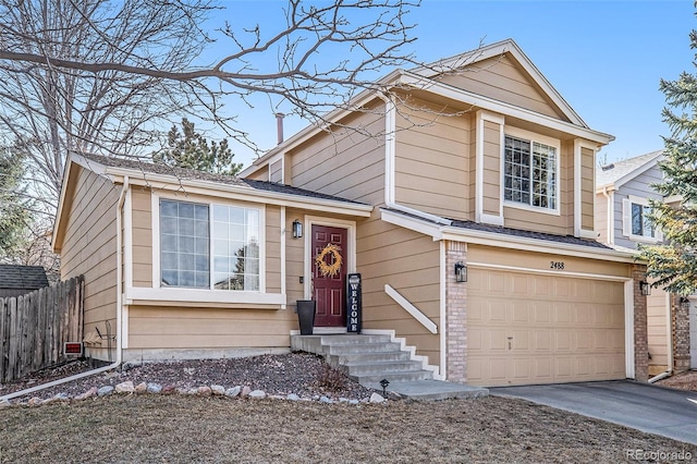 view of front facade with brick siding, an attached garage, driveway, and fence