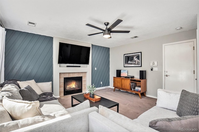 carpeted living area with visible vents, baseboards, ceiling fan, and a fireplace