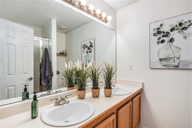 bathroom featuring double vanity, visible vents, a stall shower, and a sink