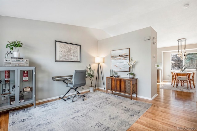 home office featuring a chandelier, baseboards, lofted ceiling, and wood finished floors