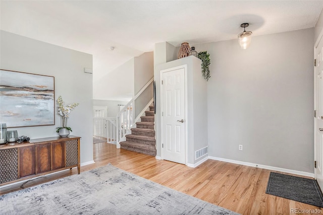 foyer featuring vaulted ceiling, stairway, baseboards, and wood finished floors