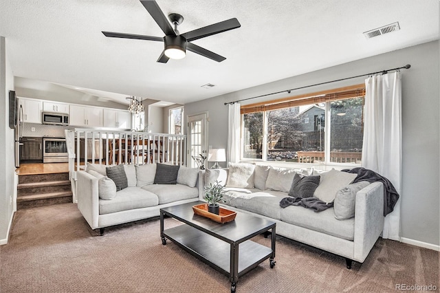 living room featuring ceiling fan with notable chandelier, carpet flooring, a healthy amount of sunlight, and baseboards