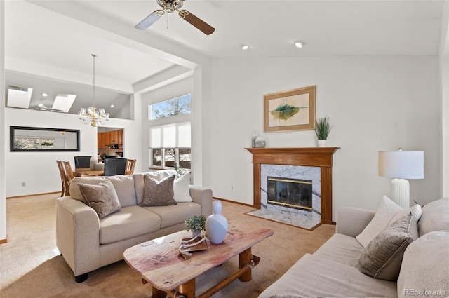 living room with light carpet, a high end fireplace, ceiling fan with notable chandelier, and a towering ceiling