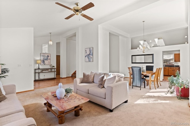 carpeted living room with ceiling fan with notable chandelier