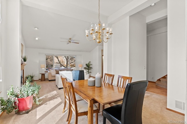 dining room featuring light carpet and ceiling fan with notable chandelier