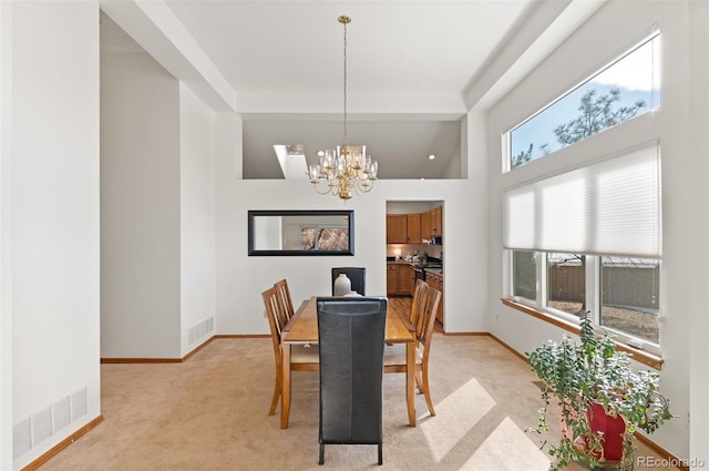 carpeted dining room featuring a towering ceiling and a chandelier