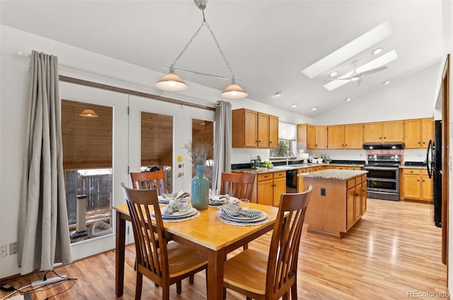 dining area with high vaulted ceiling, a skylight, sink, and light hardwood / wood-style flooring