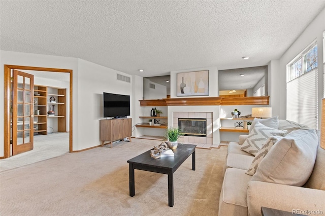 living room featuring a textured ceiling, light colored carpet, and a tiled fireplace