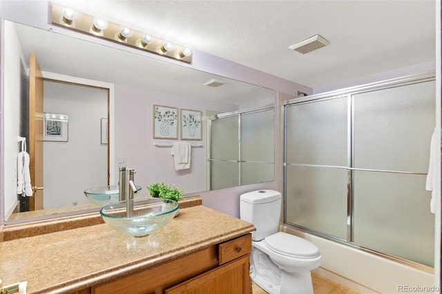 full bathroom with hardwood / wood-style floors, combined bath / shower with glass door, vanity, and toilet