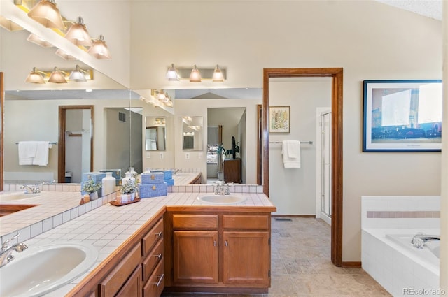 bathroom with tile patterned floors, a relaxing tiled tub, and vanity