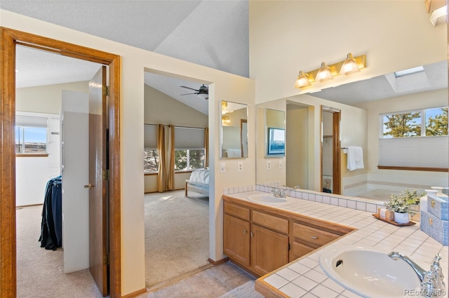 bathroom with lofted ceiling, vanity, ceiling fan, a bath, and a textured ceiling