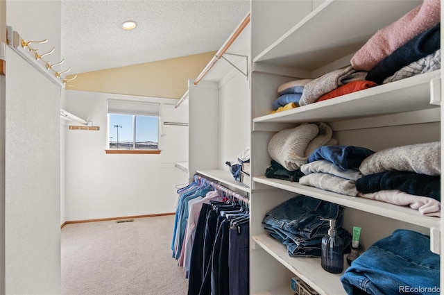 walk in closet with carpet floors and vaulted ceiling