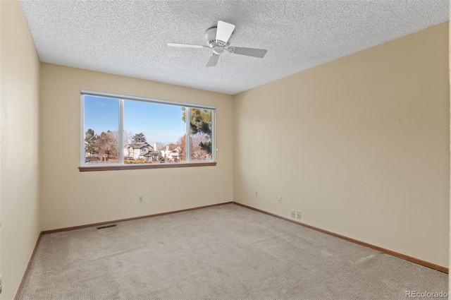 spare room with ceiling fan, a textured ceiling, and light carpet