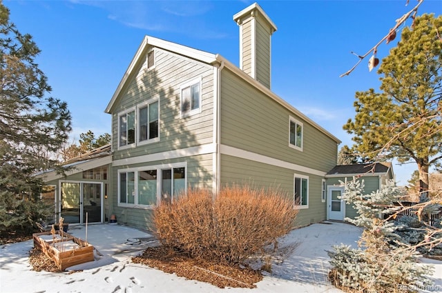 snow covered back of property with a patio