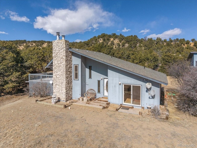 rear view of property with entry steps, a chimney, and a wooden deck