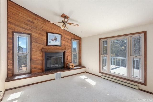 unfurnished living room with a baseboard radiator, visible vents, plenty of natural light, carpet, and a glass covered fireplace