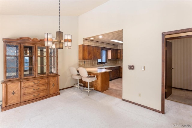 interior space featuring a kitchen breakfast bar, brown cabinetry, light countertops, and light colored carpet