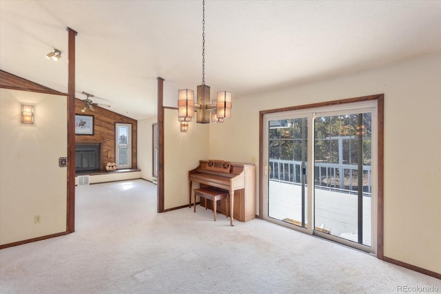 carpeted dining space with vaulted ceiling, a fireplace with raised hearth, ceiling fan with notable chandelier, and baseboards