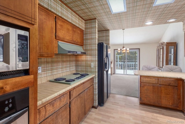 kitchen with stainless steel microwave, black fridge with ice dispenser, brown cabinetry, electric stovetop, and under cabinet range hood