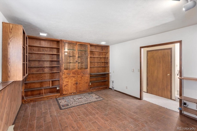 interior space featuring a textured ceiling, baseboards, and wood finished floors