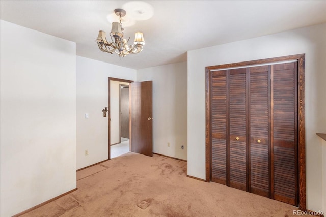 unfurnished bedroom featuring a notable chandelier, a closet, baseboards, and light colored carpet