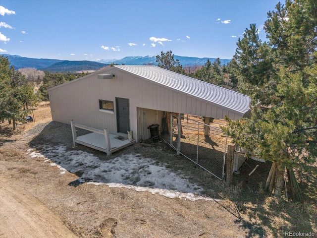 view of side of property with metal roof, a standing seam roof, an outdoor structure, and a mountain view