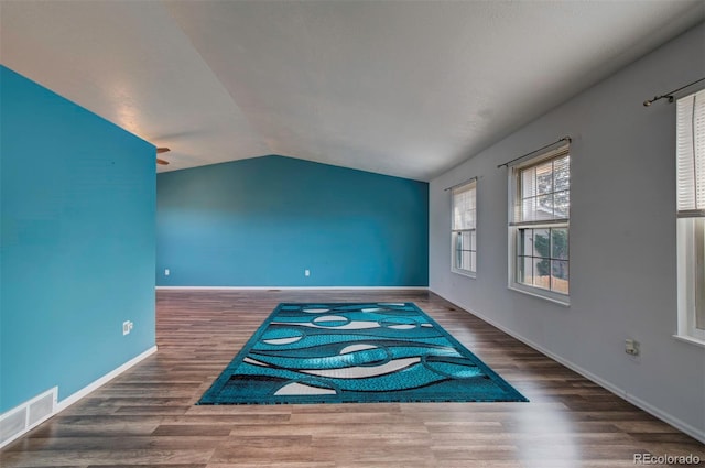 spare room featuring dark hardwood / wood-style flooring and lofted ceiling