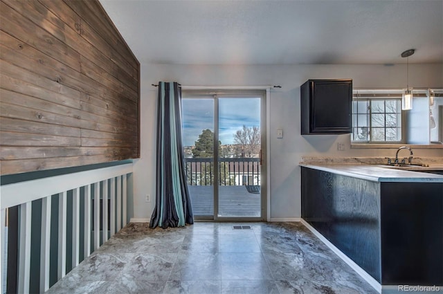 kitchen featuring a wealth of natural light, sink, pendant lighting, and wood walls