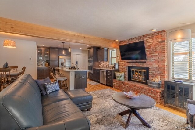 living room featuring a brick fireplace, light wood-type flooring, and recessed lighting