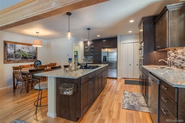 kitchen with stainless steel appliances, a sink, dark brown cabinets, and recessed lighting