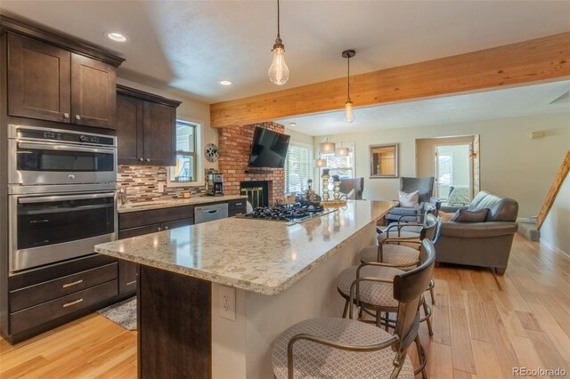 kitchen featuring open floor plan, appliances with stainless steel finishes, recessed lighting, dark brown cabinetry, and light wood-style floors