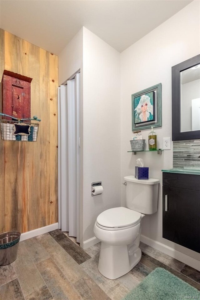 bathroom with wood finished floors, toilet, vanity, and baseboards