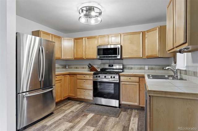 kitchen with appliances with stainless steel finishes, sink, light brown cabinetry, and light hardwood / wood-style floors