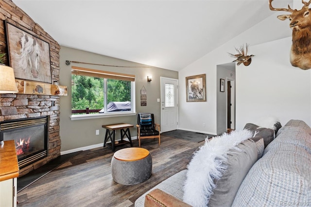 living room featuring vaulted ceiling, a stone fireplace, and dark wood-type flooring