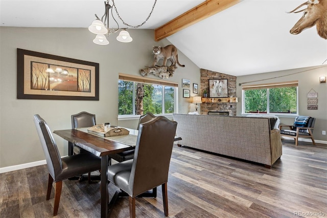 dining area featuring an inviting chandelier, wood-type flooring, a stone fireplace, and lofted ceiling with beams