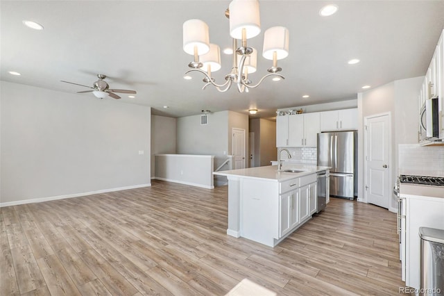 kitchen with white cabinets, decorative light fixtures, backsplash, stainless steel appliances, and ceiling fan with notable chandelier