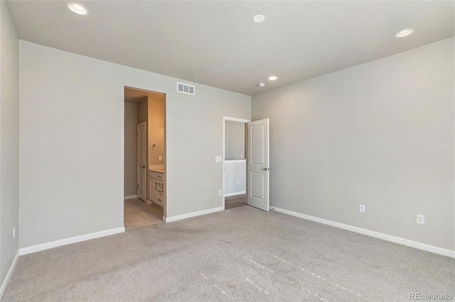 unfurnished bedroom with connected bathroom and light carpet