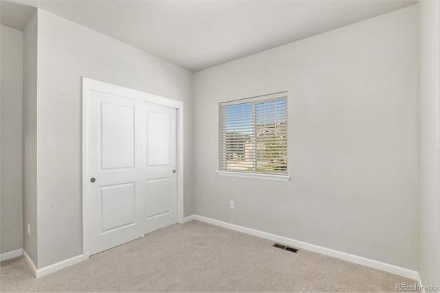 unfurnished bedroom featuring light carpet and a closet