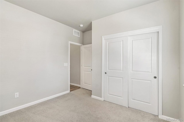 unfurnished bedroom with light carpet and a closet