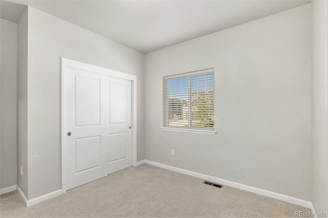 unfurnished bedroom featuring light colored carpet and a closet