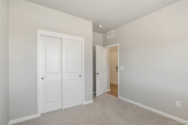 unfurnished bedroom featuring light colored carpet and a closet