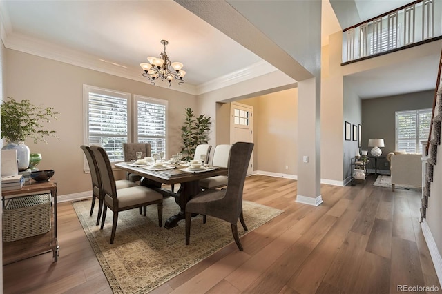 dining area featuring an inviting chandelier, ornamental molding, light wood finished floors, and baseboards
