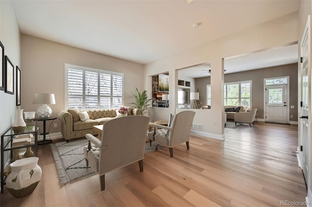 living room with light wood-type flooring, baseboards, and ceiling fan