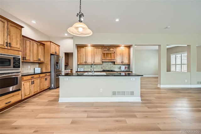 kitchen featuring dark countertops, appliances with stainless steel finishes, light wood-style flooring, and visible vents