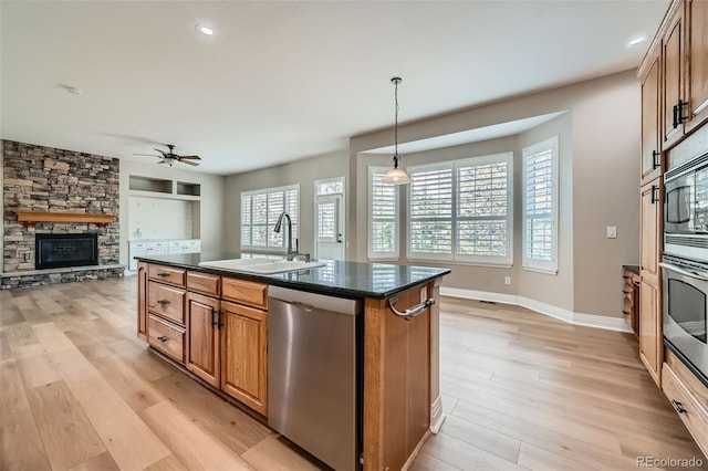 kitchen featuring a ceiling fan, appliances with stainless steel finishes, a sink, and light wood-style flooring